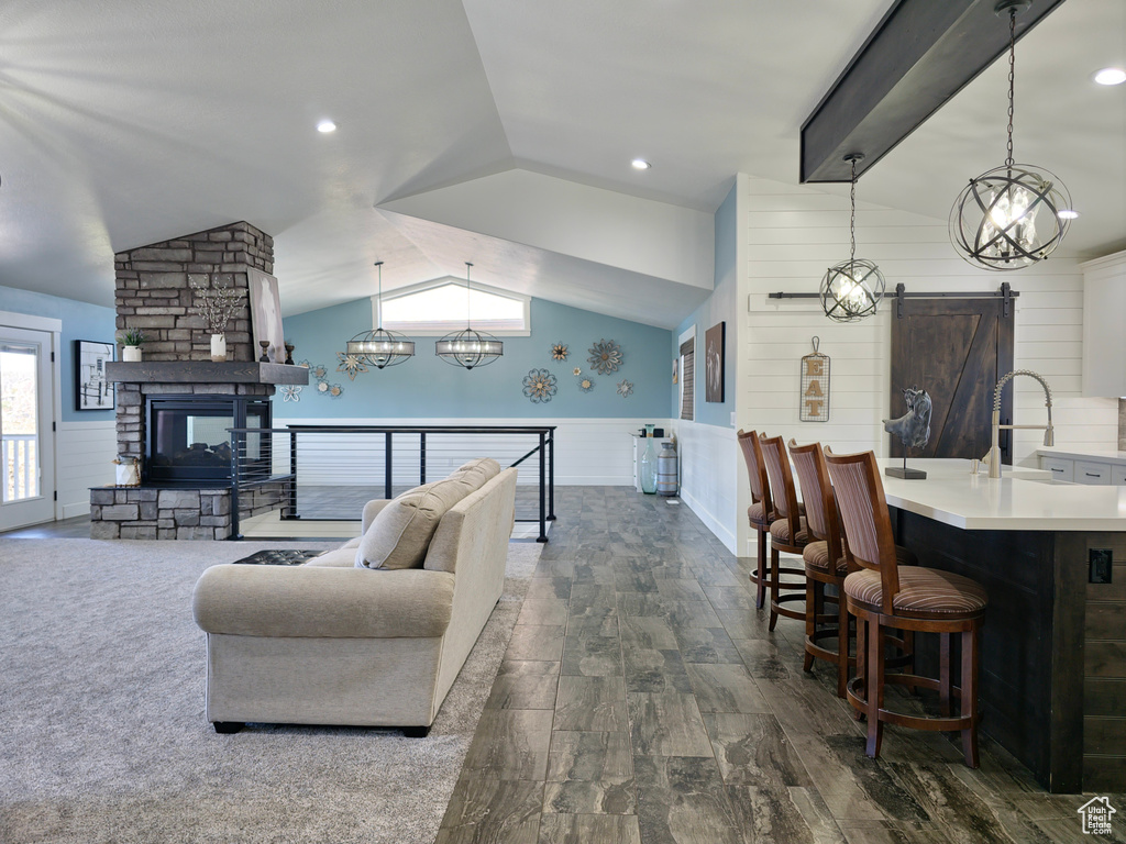 Living area featuring vaulted ceiling, dark wood-type flooring, a barn door, wainscoting, and a chandelier