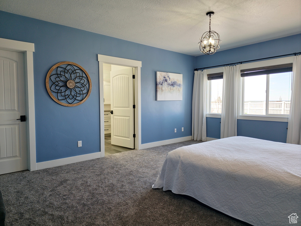 Bedroom featuring carpet floors, baseboards, a chandelier, and a textured ceiling