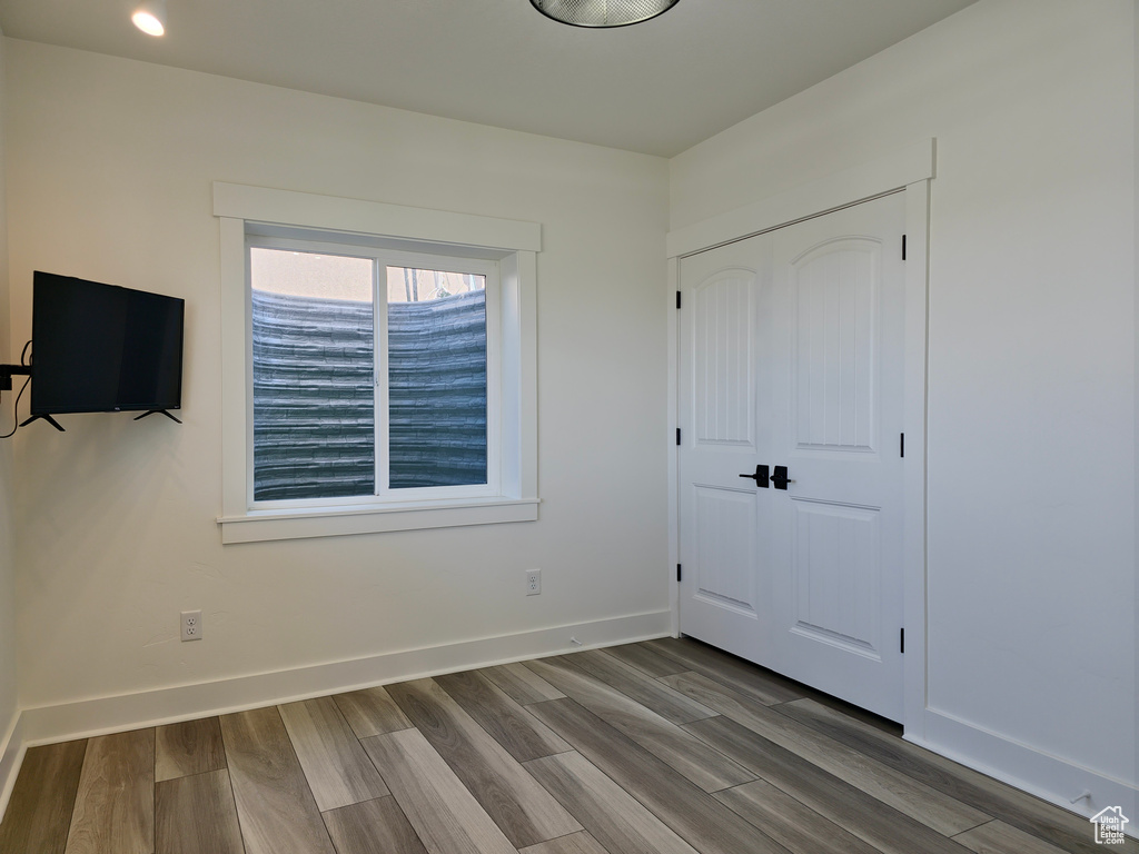 Unfurnished bedroom with wood finished floors, a closet, and baseboards