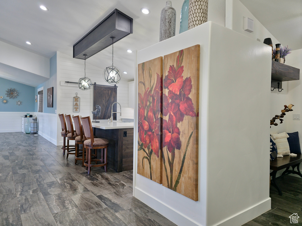 Bar area featuring wainscoting, recessed lighting, hanging light fixtures, lofted ceiling, and a barn door