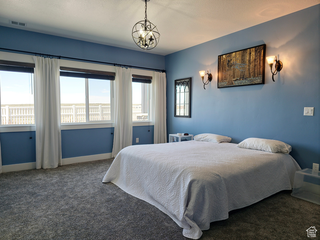 Bedroom featuring carpet, baseboards, and a chandelier
