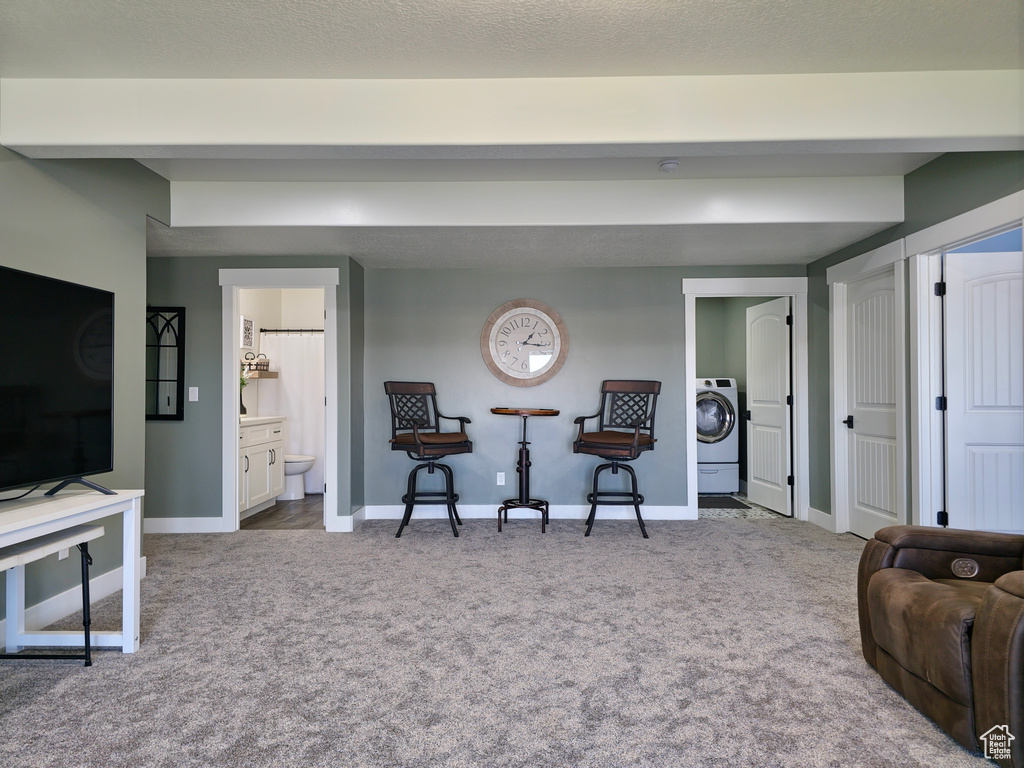 Living room featuring washer / dryer, carpet floors, and baseboards