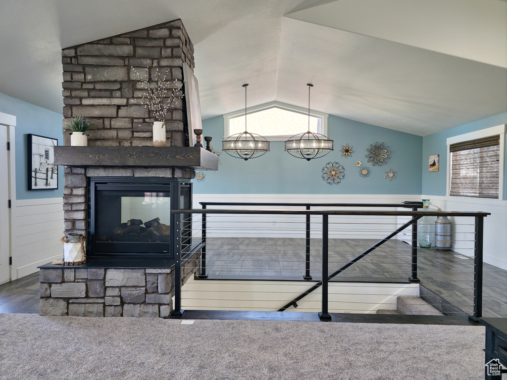 Living area featuring vaulted ceiling, a multi sided fireplace, wood finished floors, and wainscoting