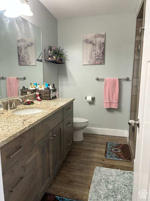 Full bathroom featuring wood finished floors, baseboards, vanity, and toilet