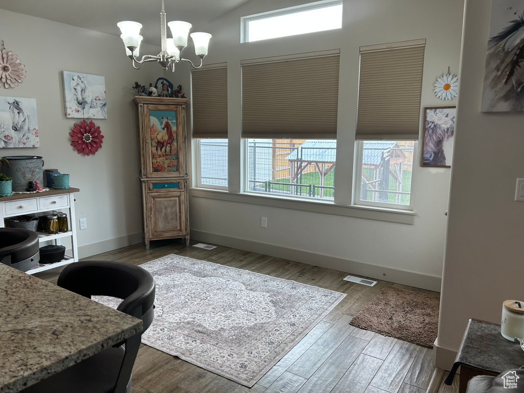 Dining area featuring healthy amount of natural light, wood finished floors, and a chandelier