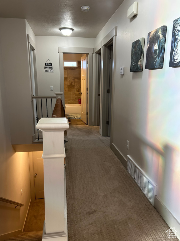 Hall with carpet, an upstairs landing, and baseboards