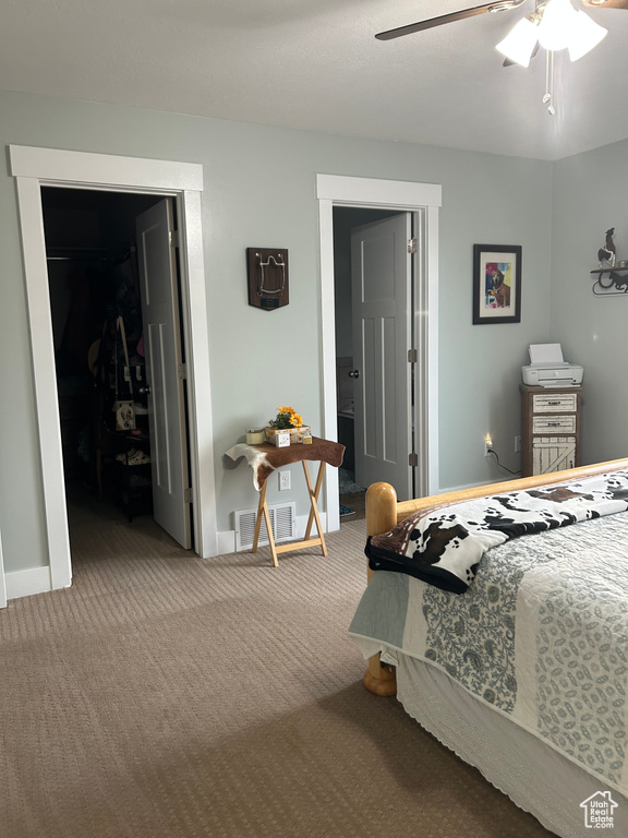 Carpeted bedroom featuring a spacious closet, baseboards, a closet, ceiling fan, and ensuite bathroom