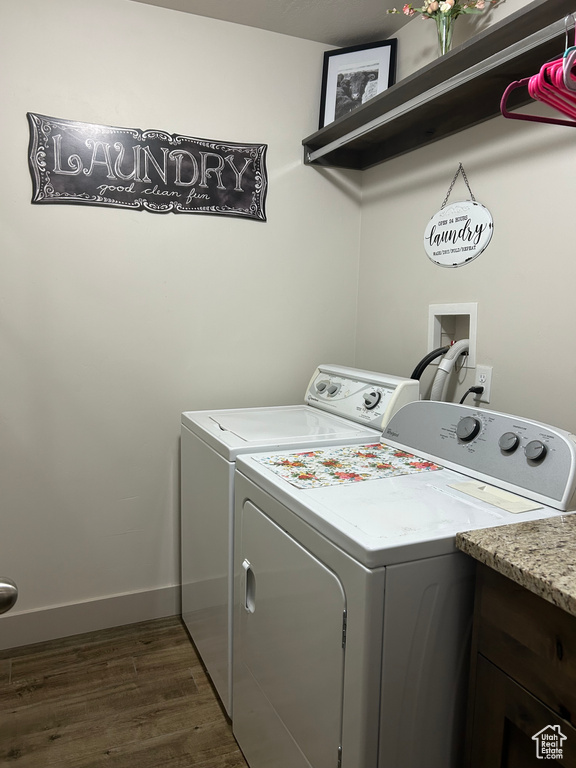 Clothes washing area with washing machine and dryer, dark wood finished floors, and baseboards
