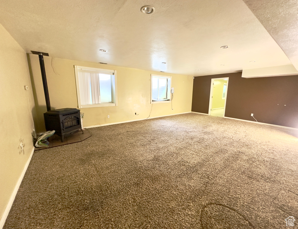 Spare room featuring a wood stove, baseboards, and carpet
