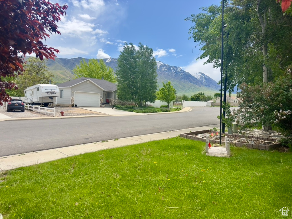 View of asphalt street featuring a mountain view, sidewalks, and curbs