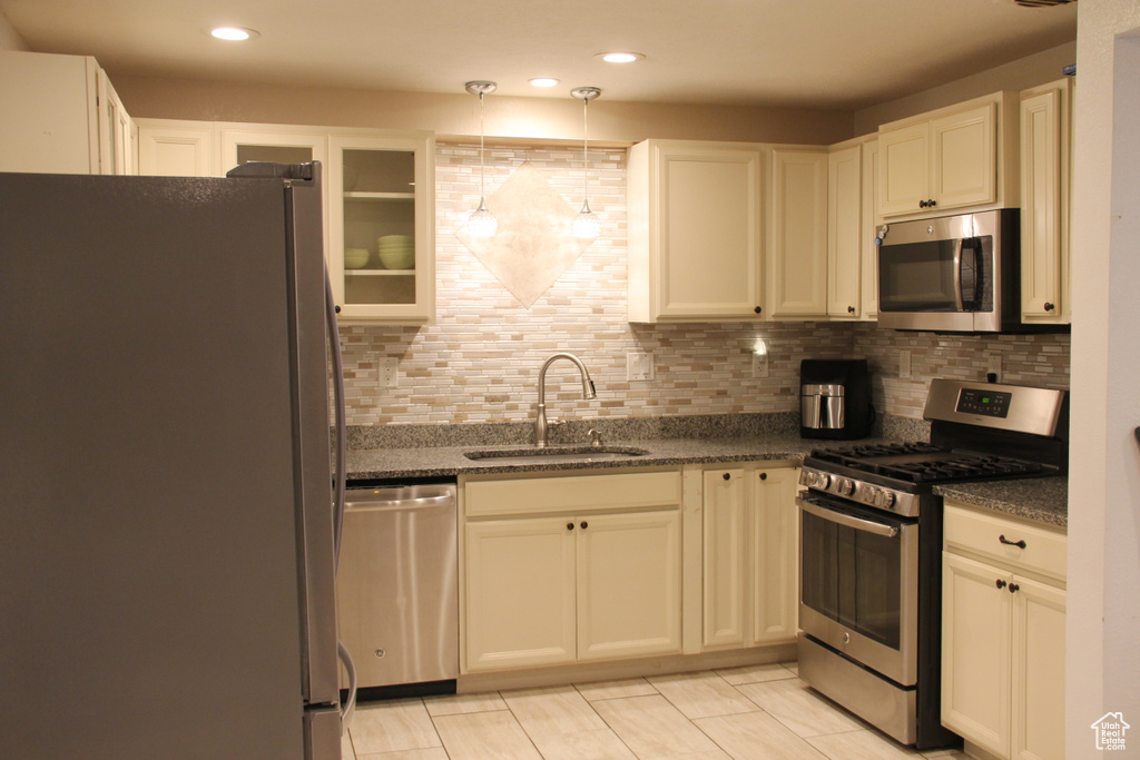 Kitchen featuring stainless steel appliances, a sink, decorative backsplash, dark stone countertops, and recessed lighting