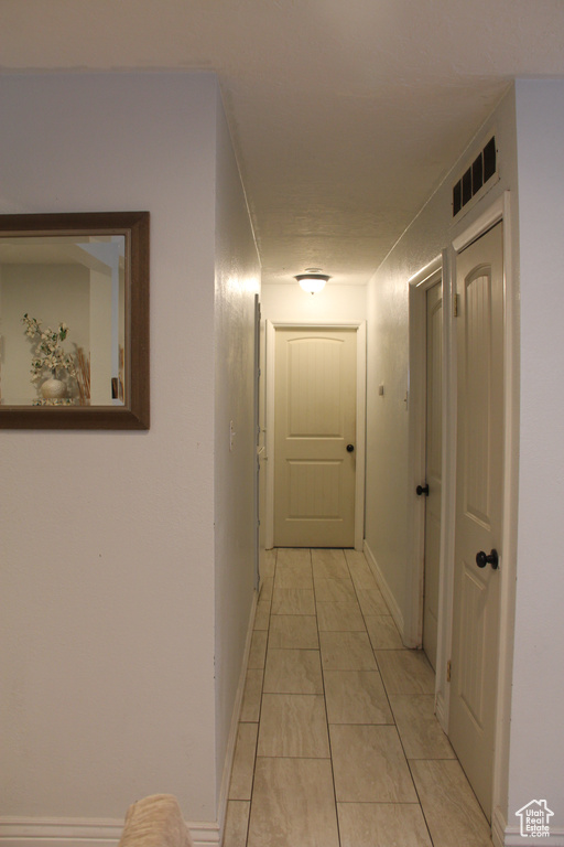 Corridor featuring baseboards and light tile patterned floors