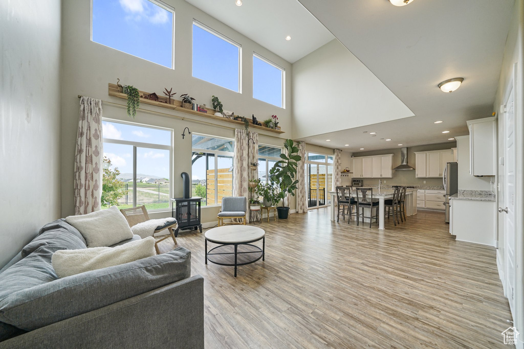 Living area featuring a towering ceiling, light wood-type flooring, and recessed lighting