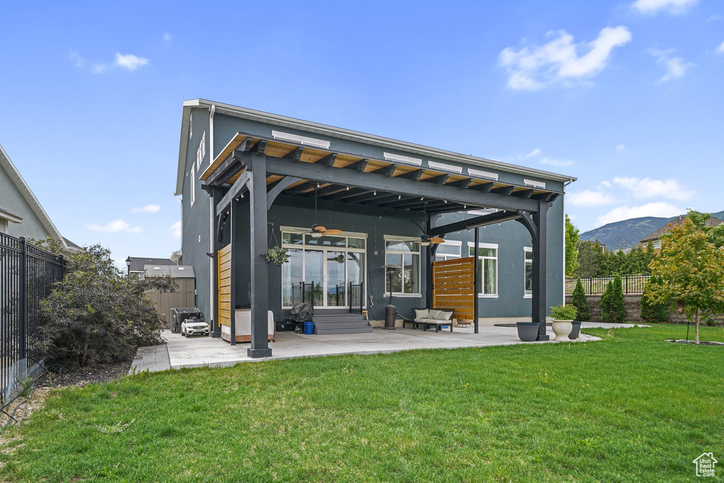 Back of property with ceiling fan, a patio, and a mountain view