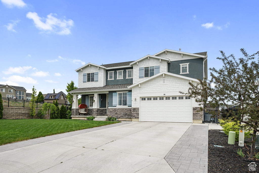 Craftsman inspired home featuring covered porch, driveway, stone siding, and a garage