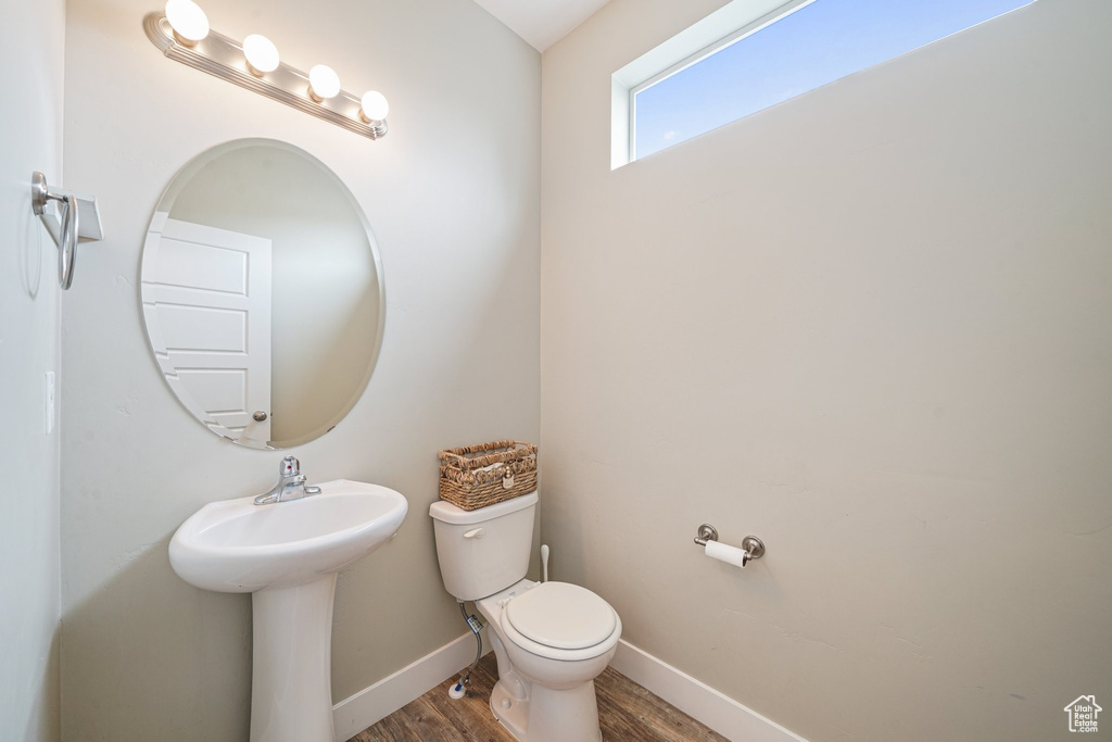 Bathroom featuring toilet, wood finished floors, and baseboards