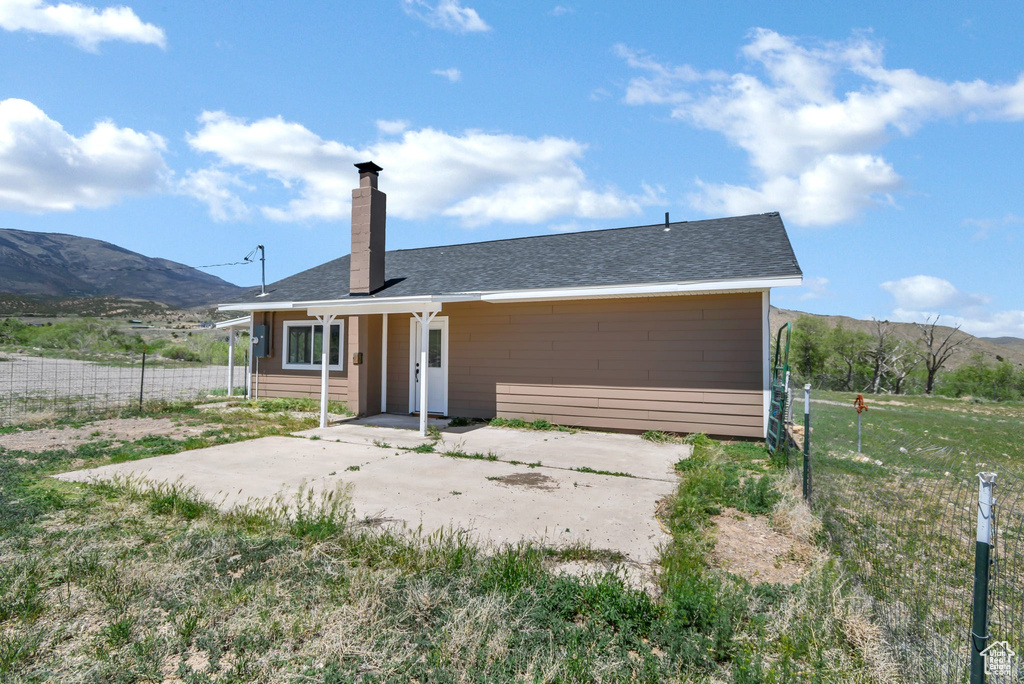Rear view of property with a chimney, a mountain view, fence, and a patio area