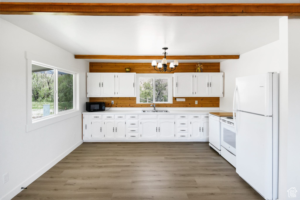 Kitchen with white appliances, a sink, a chandelier, beam ceiling, and white cabinets