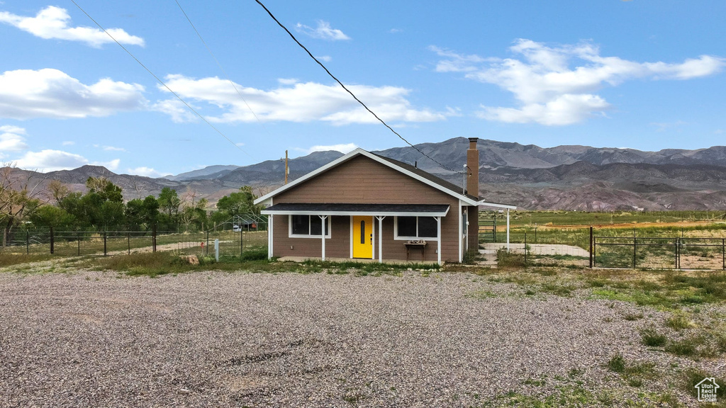 Bungalow with a mountain view, fence, a chimney, a porch, and a rural view