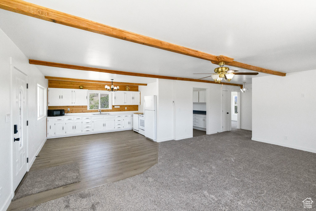 Unfurnished living room featuring a chandelier, a sink, baseboards, beam ceiling, and a ceiling fan