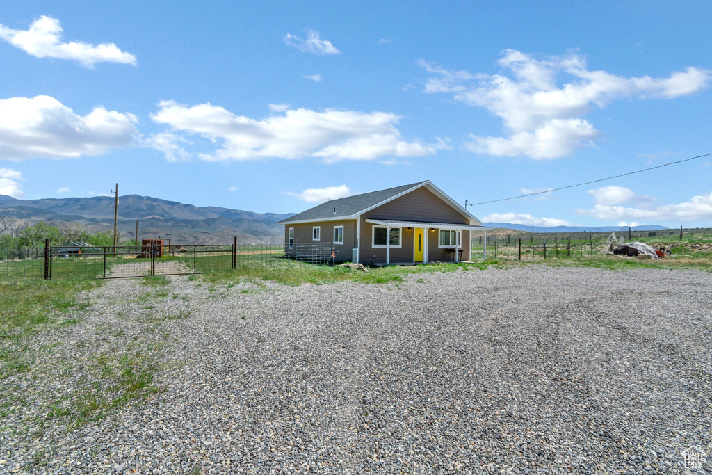 View of front of house featuring fence, a mountain view, a gate, and a view of countryside