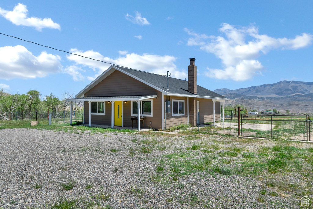 View of front of house featuring a chimney, fence, a mountain view, and a gate