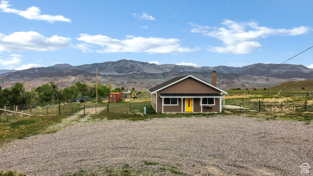 View of front of home featuring a mountain view, a chimney, and fence