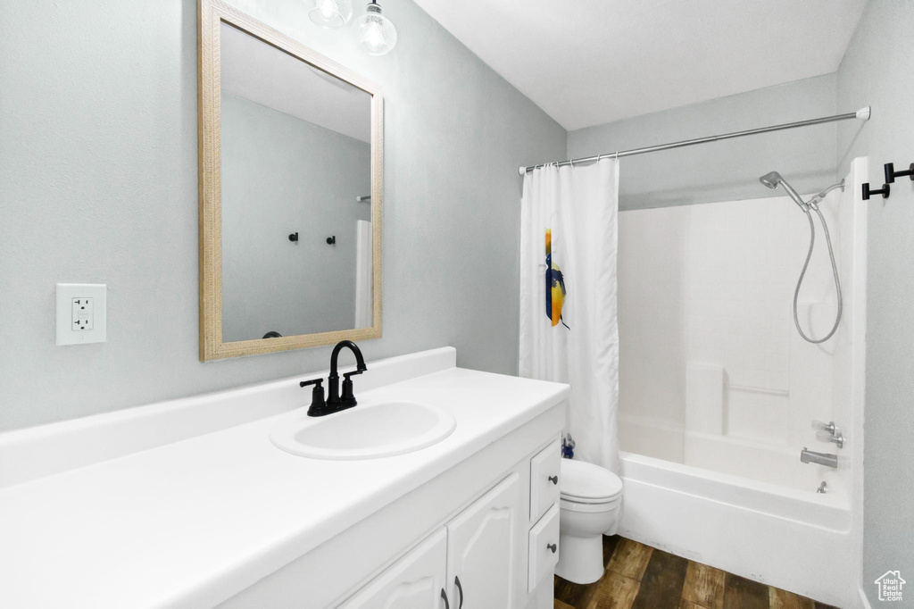 Full bath with wood finished floors, toilet, vanity, and shower / bath combination with curtain