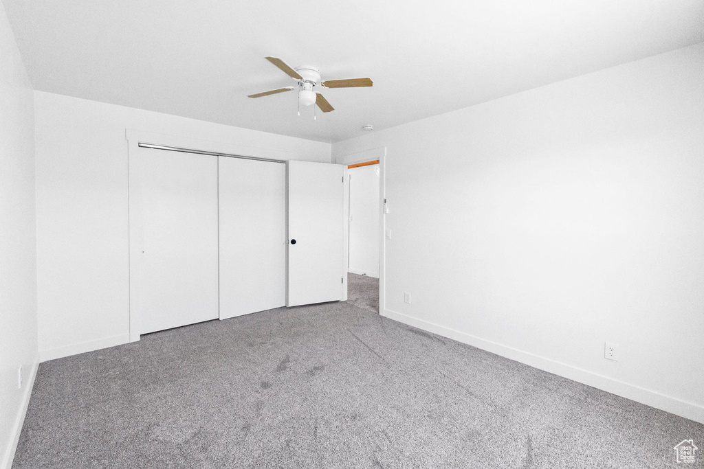 Unfurnished bedroom with carpet, a closet, baseboards, and a ceiling fan