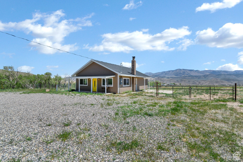 Back of house with fence, a chimney, a mountain view, and a gate