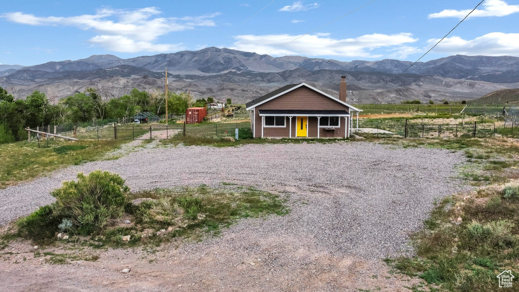 View of front of house with fence, a mountain view, covered porch, and a view of countryside