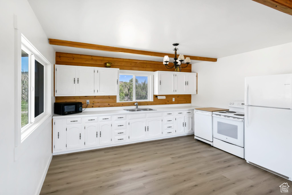 Kitchen with white appliances, a sink, a chandelier, beamed ceiling, and white cabinetry