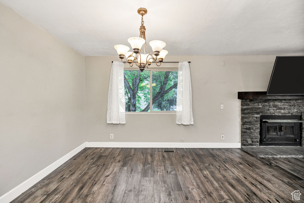 Unfurnished dining area with a chandelier, baseboards, and wood finished floors