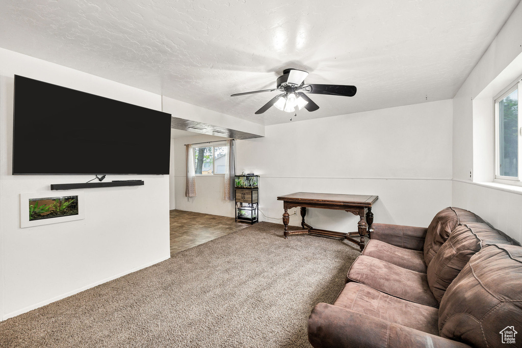 Carpeted living area with ceiling fan