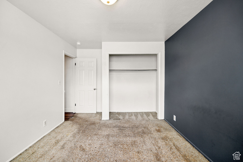 Unfurnished bedroom featuring carpet, a closet, and baseboards