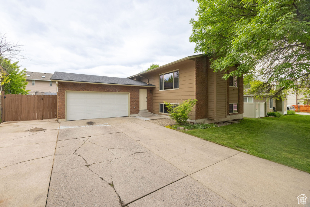 Split level home with concrete driveway, brick siding, and an attached garage