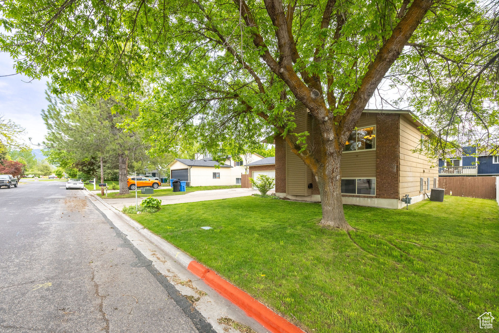 View of front of house featuring concrete driveway, a front lawn, brick siding, and central AC