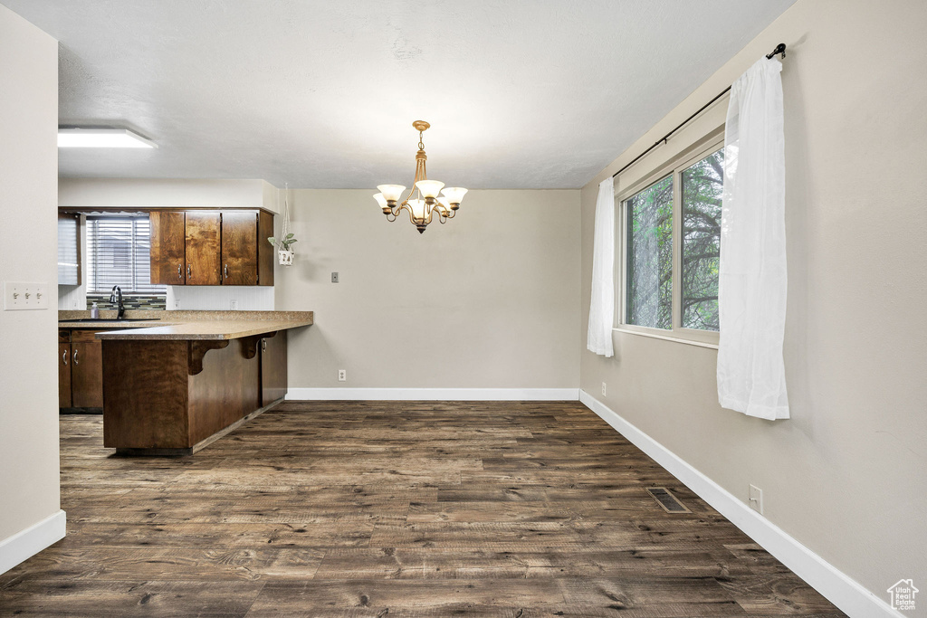 Kitchen with plenty of natural light, a chandelier, a breakfast bar area, and a peninsula