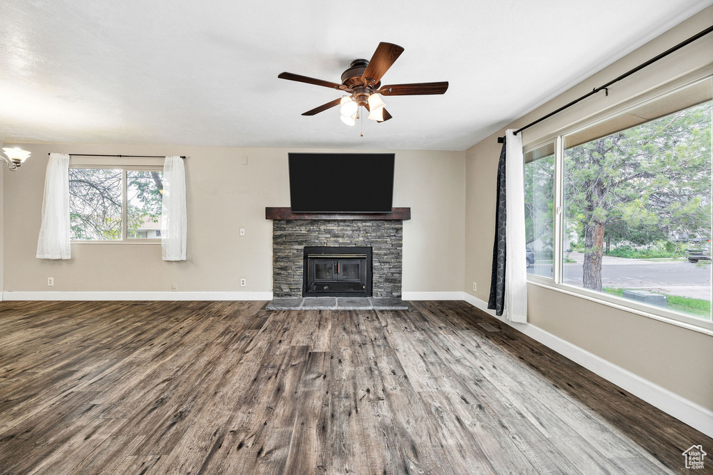 Unfurnished living room with wood finished floors, a ceiling fan, a fireplace, and baseboards