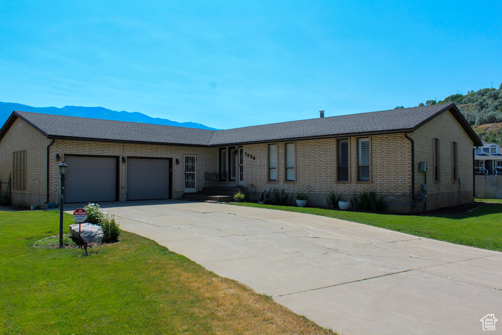 Ranch-style home with brick siding, a garage, driveway, and a front yard