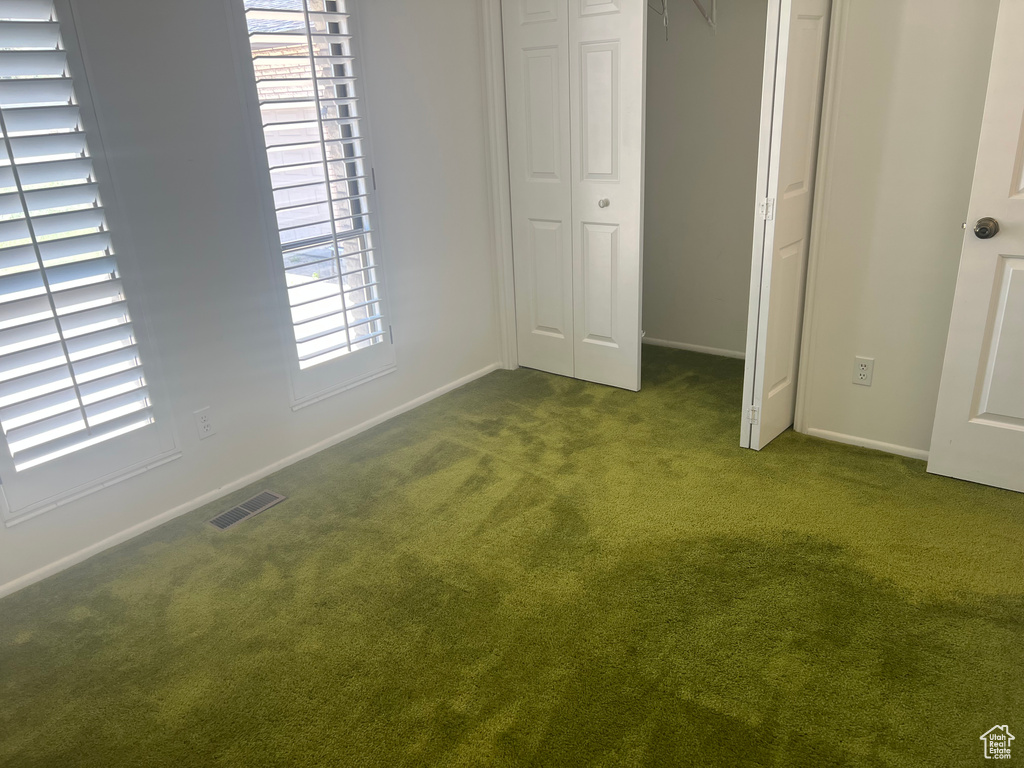 Unfurnished bedroom featuring dark carpet, a closet, and baseboards