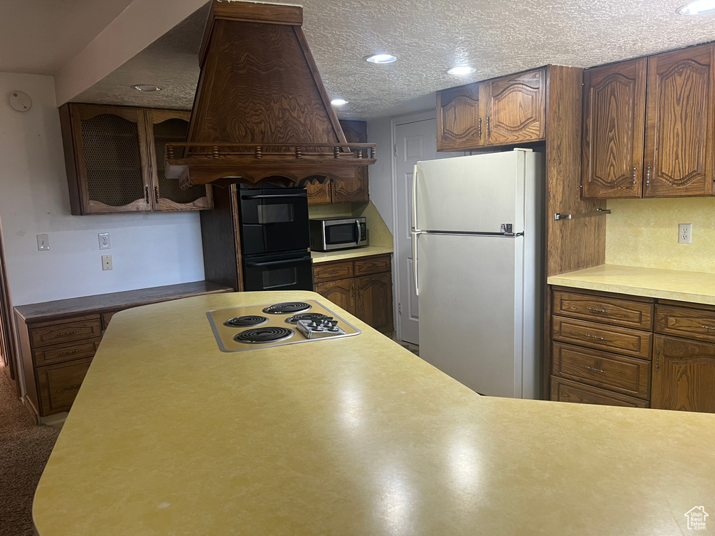 Kitchen featuring freestanding refrigerator, stainless steel microwave, electric cooktop, recessed lighting, and light countertops