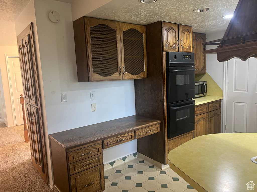 Kitchen featuring stainless steel microwave, a textured ceiling, and glass insert cabinets