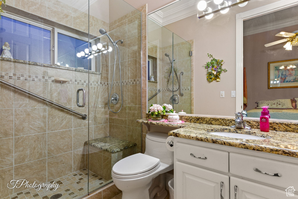 Full bath featuring ornamental molding, a shower stall, toilet, vanity, and ceiling fan