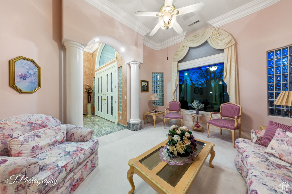 Carpeted living room featuring ornate columns, ornamental molding, and ceiling fan