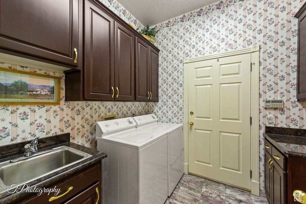 Laundry area featuring cabinet space, wallpapered walls, and washer and clothes dryer