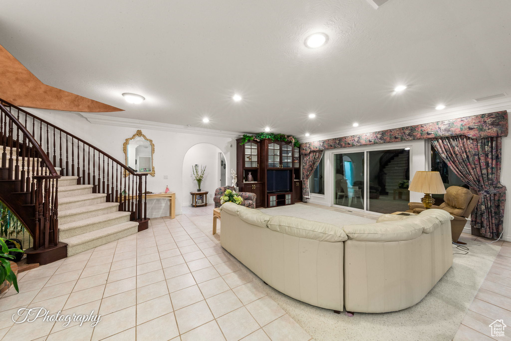 Living room featuring arched walkways, stairs, ornamental molding, and recessed lighting