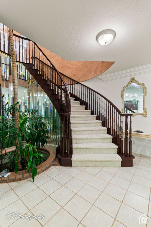 Staircase featuring tile patterned floors and ornamental molding
