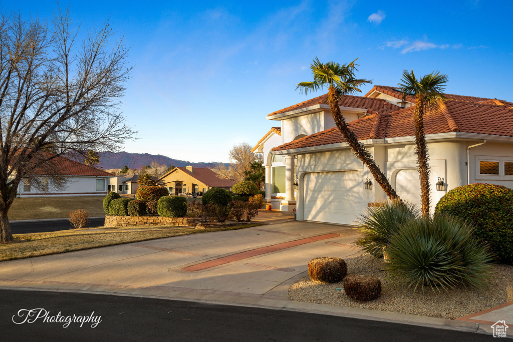 Mediterranean / spanish-style house with stucco siding, a tile roof, a mountain view, an attached garage, and driveway