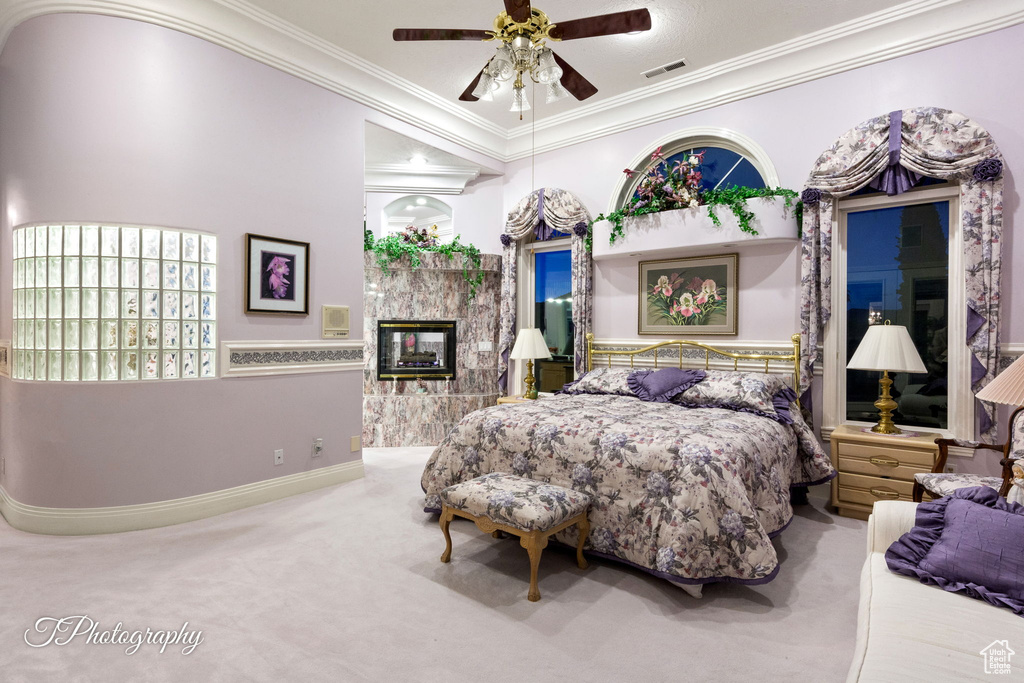 Carpeted bedroom with crown molding, a fireplace, baseboards, and ceiling fan